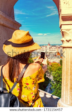 A young woman in the Castle of Budapest in Hungary taking pictures of the city with her phone.