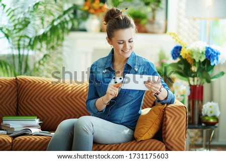 happy stylish woman in jeans shirt with tablet PC study online at modern home in sunny day.