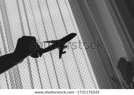 Silhouette of a happy child girl playing with a toy airplane in her room by the window. Dream to fly. Close the borders of air travel.