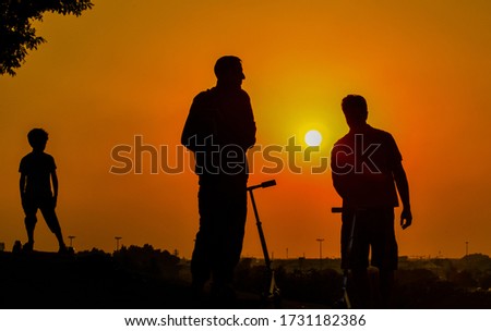 People or Family Silhouette Enjoying in the Park at Sunset, Silhouettes Against the Backdrop of a Bright  
