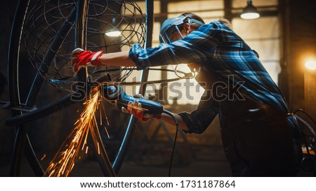Beautiful Female Artist Uses an Angle Grinder to Make Brutal Metal Sculpture in Studio. Tomboy Girl Polishes Metal Tube with Sparks Flying Off It. Contemporary Fabricator Creating Abstract Steel Art. Royalty-Free Stock Photo #1731187864