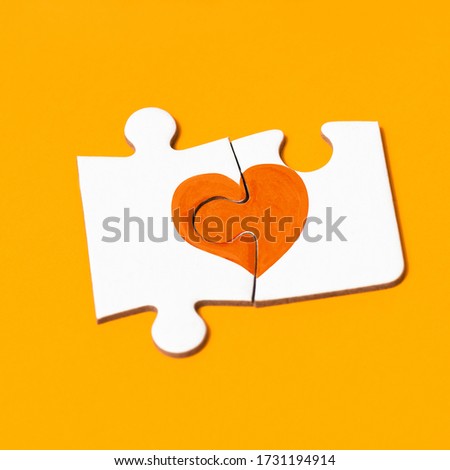 closeup of two pieces of a puzzle forming an orange heart, in support of people affected by multiple sclerosis, on an orange background Royalty-Free Stock Photo #1731194914
