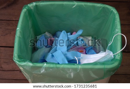 End Covid-19 pandemic. Used face masks and gloves throwaway in trash can. Disposing medical waste, shoe covers, alcohol wipes, empty plastic bottles of sanitizers Royalty-Free Stock Photo #1731235681