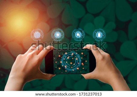 Hand holding smartphone and virtual screen icon to analyze the needs of trees in nature for modern agriculture on green leaf background with morning light. Smart farmer concept.