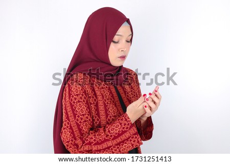 Young Asian Islam Muslim woman in headscarf and hijab prays with her hands up in air with serious face. Indonesian woman. Religion praying concept isolated on white background.
