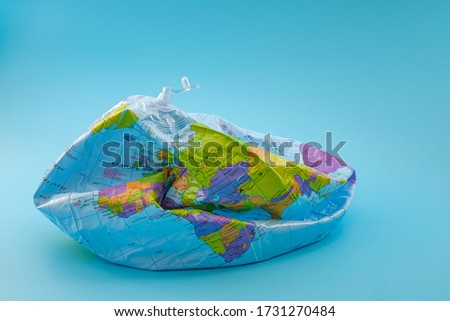 Global warming, climate catastrophe and environmental trouble concept with deflated globe isolated on blue background Royalty-Free Stock Photo #1731270484