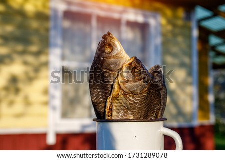 Dried fish in a white mug with a country house background
