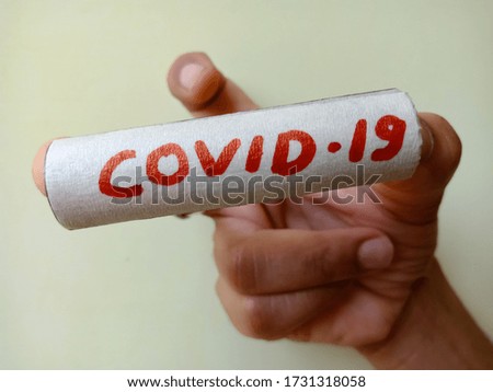 Covid 19 text displayed on red color holded on female hand at light background.