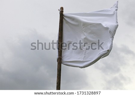 The white flag against the gray sky.  Surrender concept. Royalty-Free Stock Photo #1731328897