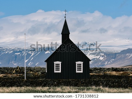 An isolated black chapel/church named Budir with mountains in the distance on the Snaefellsnes Peninsula in the southern region of Iceland