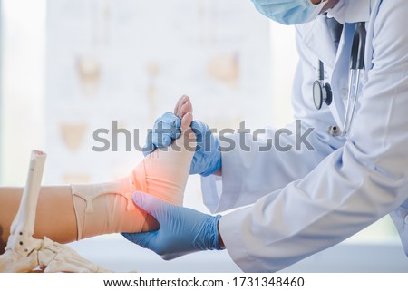 Close-up of pictures of a male orthopedic doctor or orthopedic doctor Wear a medical mask and medical gloves. Going to analyze the cause of ankle bone degeneration In his office at the hospital Royalty-Free Stock Photo #1731348460