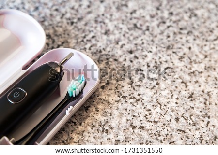 Modern black sonic or electric toothbrush in case on flat lay background with copy space. Concept of professional oral care and healthy teeth by using ultrasonic toothbrush