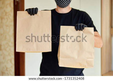 Courier in black hold go box food, delivery service, Takeaway restaurants food delivery to home door. Stay at home safe lives from coronavirus outbreak. Contactless delivery service under quarantine.