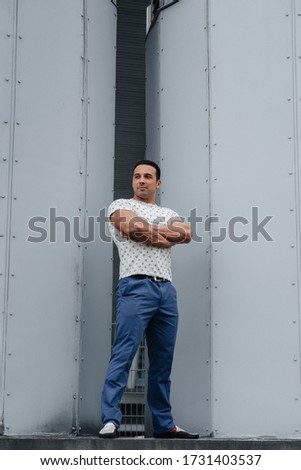 A young man stands in the open air near technical structures
