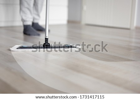 before and after cleaning concept - man cleaning wooden floor with mop in living room - copy space over wooden parquet Royalty-Free Stock Photo #1731417115