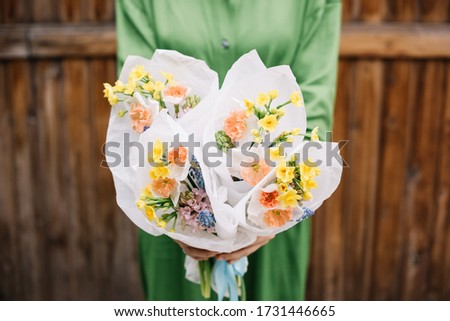 Very nice young woman holding many small and beautiful bouquets of fresh narcissus, hyacinths and muskari flowers in yellow, orange and blue colors, cropped photo, bouquet close up