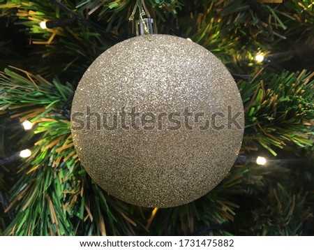 a big bronze silver sparking ball on a christmas tree