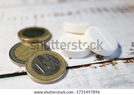 euro coins and medicine pills on a wooden background