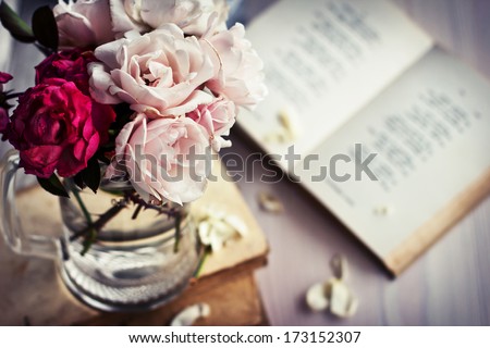 Beautiful Roses in a glass vase with books in vintage style