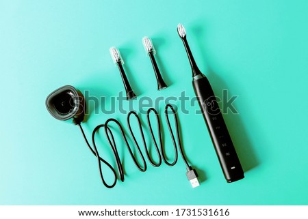 Modern rechargeable sonic or electric toothbrush set with usb charger and heads on pastel flat lay background. Concept of professional oral care and healthy teeth by using ultrasonic toothbrush