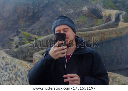 Young guy taking pictures with cellphone in winter sea