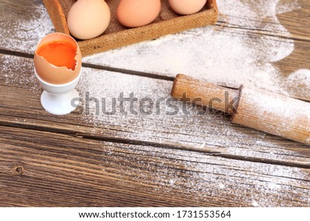 Baking cake in rural kitchen - dough recipe ingredients eggs, flour, milk, butter, sugar on vintage wooden table from above. Background layout with free text space.