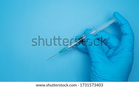Doctor hand in Medical gloves to hold syringes on blue background, Top view Blank for design copy space.