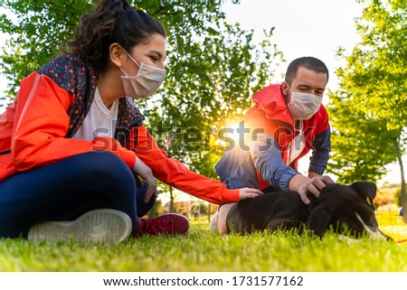 young couple wearing a protective mask is walking alone with a dog outdoors because of the corona virus pandemic covid-19