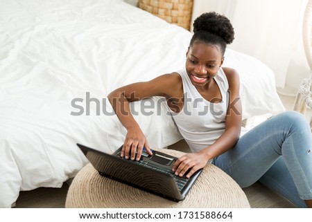 beautiful young african woman sitting on the floor with laptop