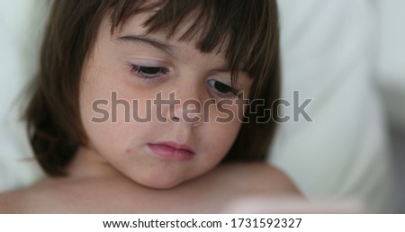 Baby girl face watching cartoon content online on smartphone device
