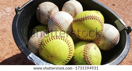 softball balls in bucket on field
