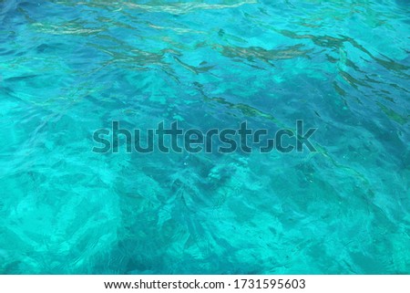 Blue glossy surface of the ocean with ripples and reflection of sunlight. In the depths of the sea. Selected sharpness. Background