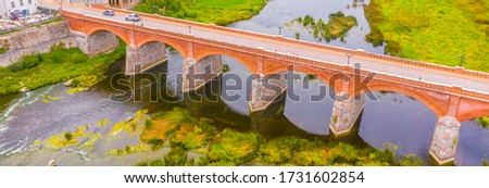 Beautiful panoramic aerial view photo from flying drone to Venta Rapid waterfall,the widest waterfall in Europe and the third longest brick bridge in Europe on a summer day in Kuldiga, Latvia.(series)