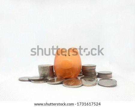 Closeup of Orange Piggy Bank is at the top of Stack Coins of Thailand isolated on white background. Royalty-Free Stock Photo #1731617524