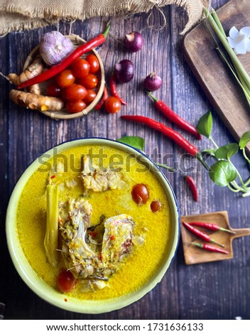 IKAN JENAHAK MASAK LEMAK CILI API- a kind of Malay traditional dish served in white plate on the table over dark background. The main ingredients  like onions, curry powder, chili and spices.