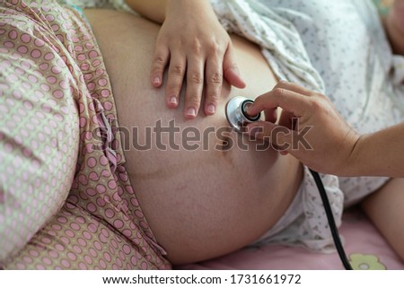 Cropped image of Man hand using stethoscope examining pregnant woman