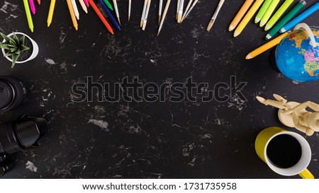 Top view of black desktop with various colorful drawing tools.