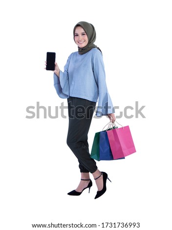 Beautiful women of muslim Indonesian holding cell phone and carrying a shopping bag isolated on white background
