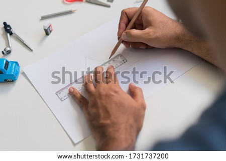 Work from home concept. Close up male hands is painting picture with  pencil in the paper on white table.