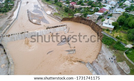 Disasters caused by global warming. Part of the destroyed dam on the river. The soil, washed out by water, caused a landslide and the destruction of houses in the river zone. Aerial View Royalty-Free Stock Photo #1731741175