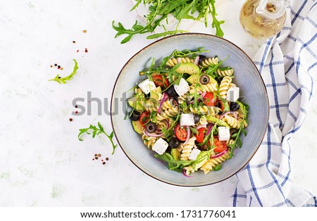 Pasta salad with tomato, avocado, black olives, red onions and cheese feta. Mediterranean cuisine. Top view, overhead, flat lay