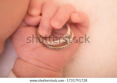 Baby hand. Newborn hand holding wedding rings. Family and love concept. Royalty-Free Stock Photo #1731791728