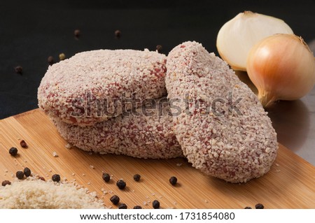 raw pork cutlets with onion in breadcrumbs