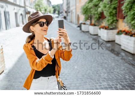 Young stylish woman with a smart phone on the old city street. Concept of happy traveling and summer vacations in the european town