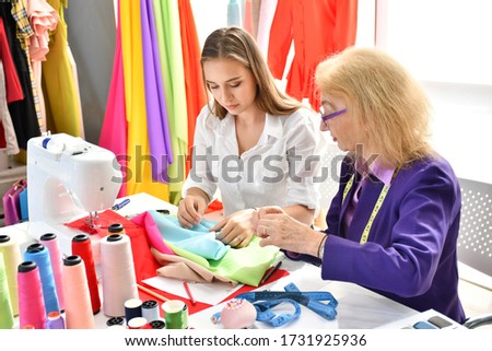 The tailor's business owner is teaching a young female employee interested in tailoring to become a fashion designer.