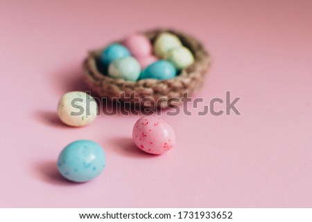 Coloeful easter eggs in nest on pastel color background with space.