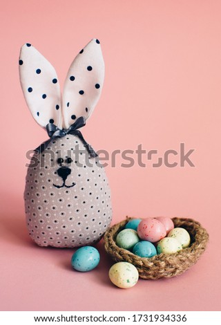 Easter bunny. Coloeful easter eggs in nest on pastel color background with space.