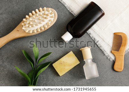 Spa composition on concrete background with copy space for text. Flat lay: lotion, SPA massage brush, solid soap, wooden hair brush, towel, green leaves. Body and skin care concept