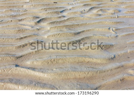 Wet sand texture on ocean shore formed by gentle waves 