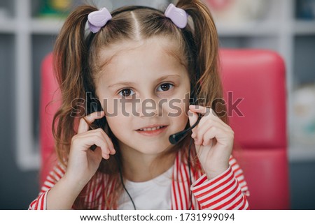 Portrait of smiling little girl wearing headphones. Happy small preschooler child in earphones have fun. Studying online on quarantine